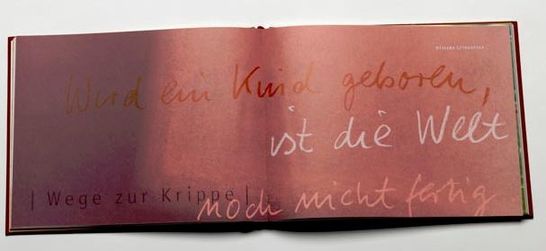 Doppelseite aus dem Buch Freude mit rotem Hintergrund, darauf der Spruch "Wird ein Kind geboren, ist die Welt noch nicht fertig". 