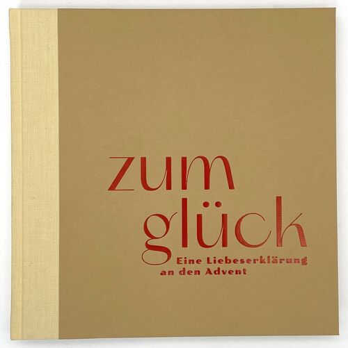 Das Cover des Buches "zum glück" ist beige mit einem Leinenrücken. Der Titel "zum glück - Eine Liebeserklärung an den Advent" ist in dunkelrot auf das Cover geprägt.